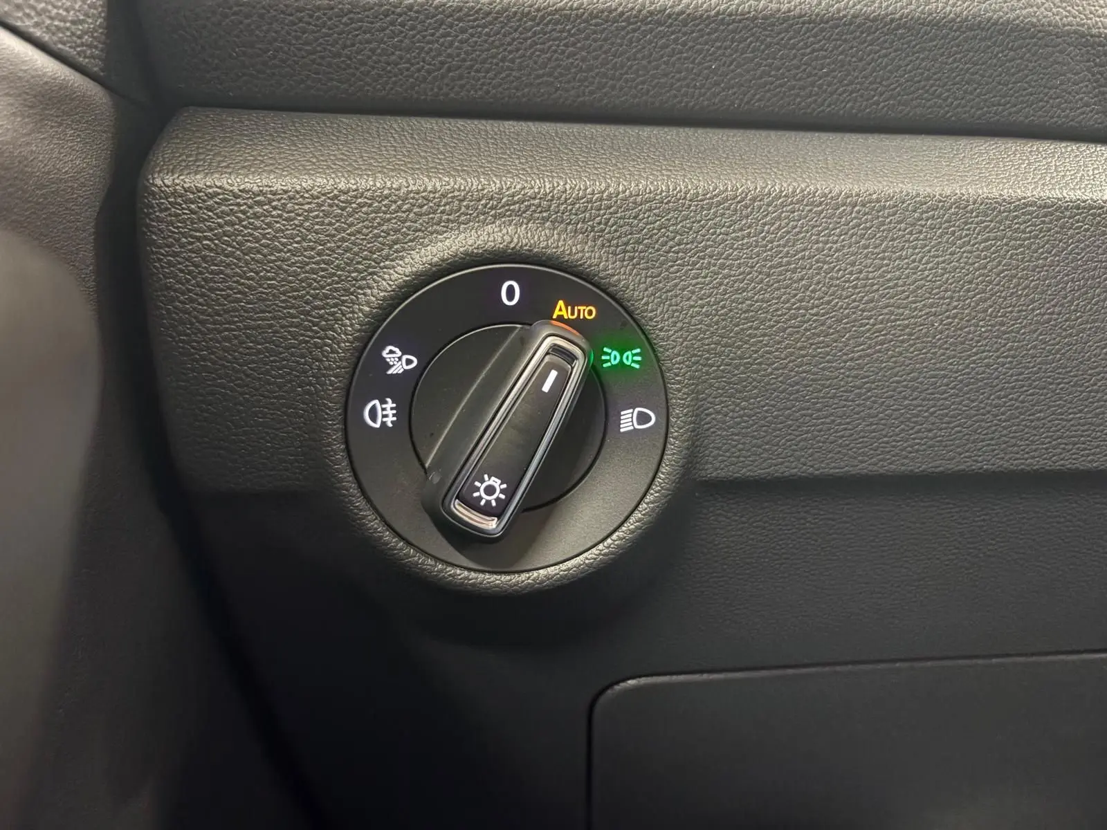 Gros plan sur le sélecteur de phares du tableau de bord noir du Volkswagen T-Roc 2025, avec éclairage automatique activé.