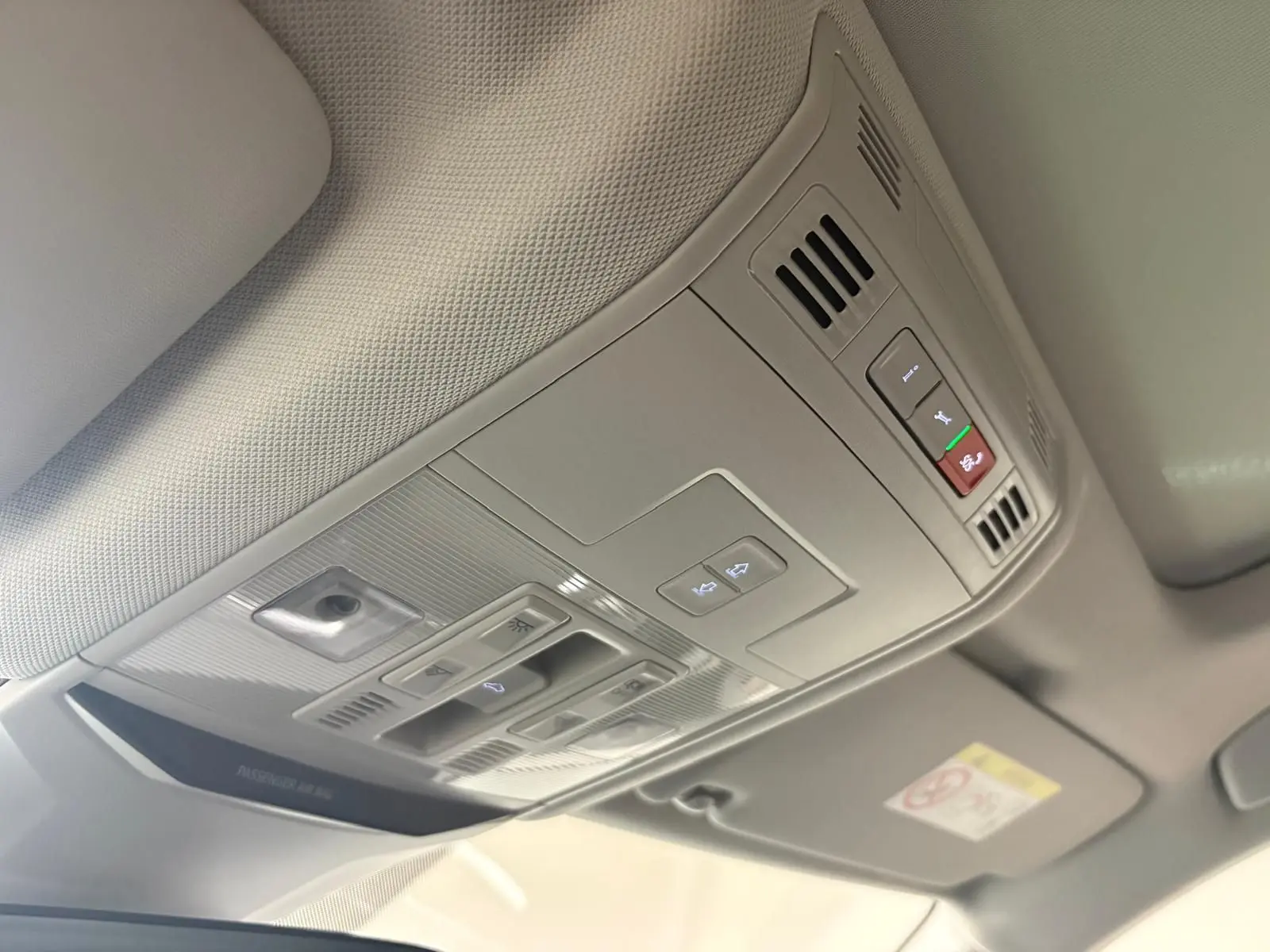 Vue intérieure du plafonnier gris clair du Volkswagen T-Roc 2025 avec commandes d'éclairage et toit ouvrant.