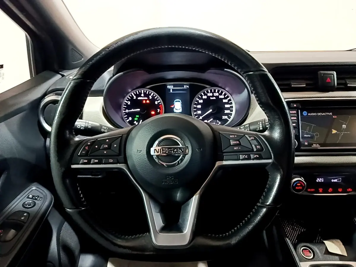 Vue intérieure centrée sur le volant cuir noir multifonctions et le tableau de bord digital de la Nissan Micra 2017.