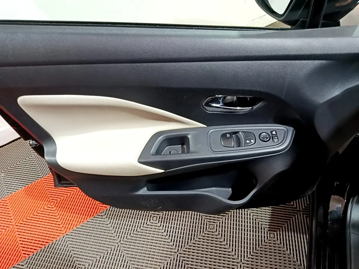 Vue intérieure côté gauche de la porte avant noire de la Nissan Micra IG-T 90 N-Connecta avec panneau beige et commandes électriques.
