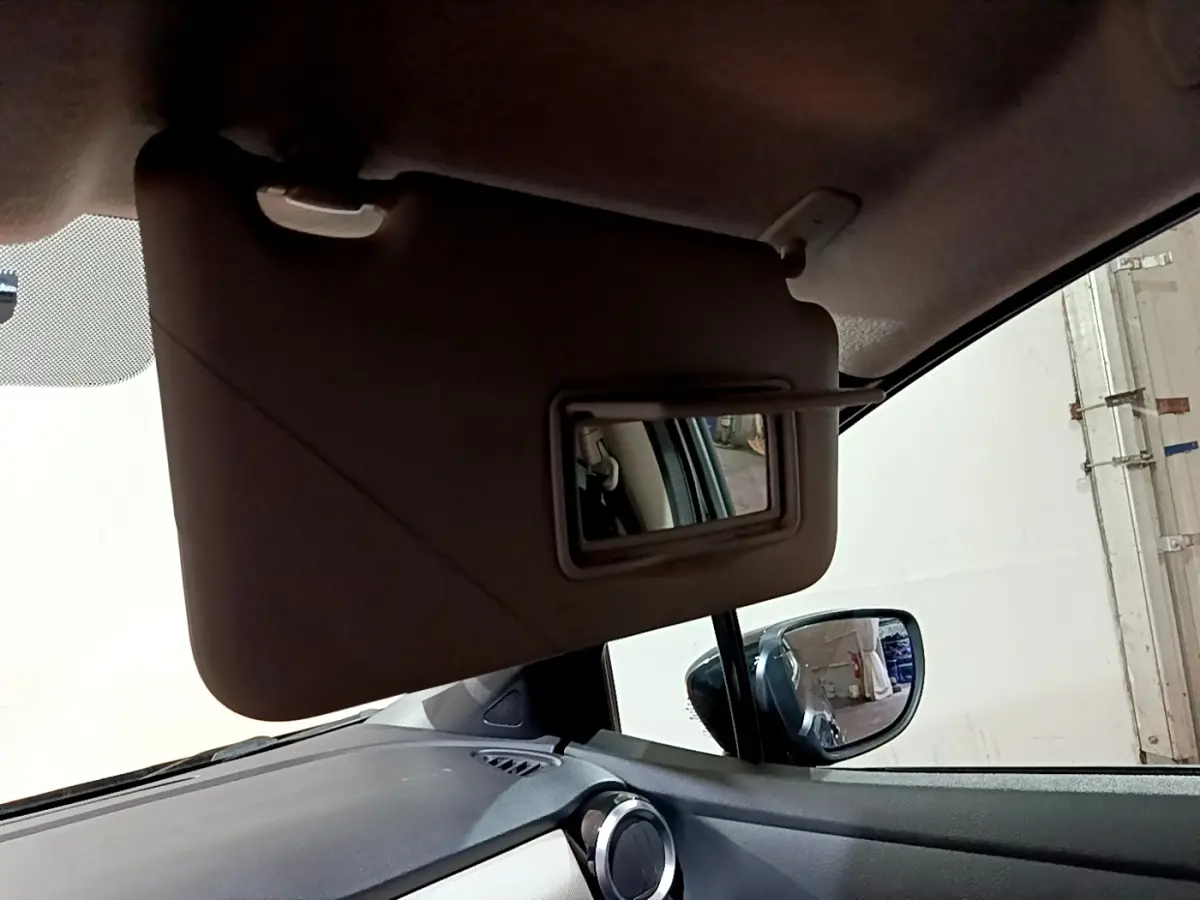 Vue intérieure rapprochée du pare-soleil avec miroir ouvert côté conducteur d'une Nissan Micra noire de 2017.