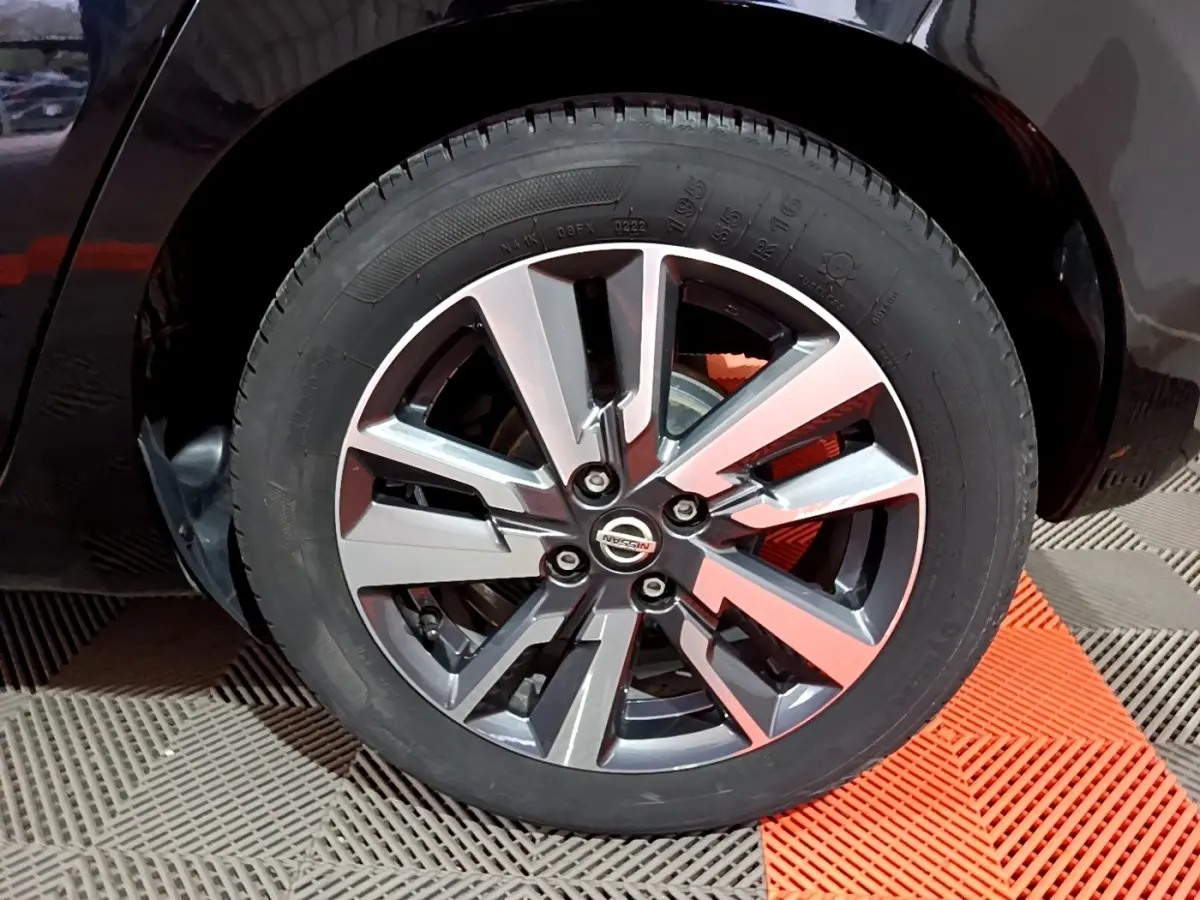 Gros plan sur la roue avant droite de la Nissan Micra noire, mettant en valeur la jante alliage au design moderne.