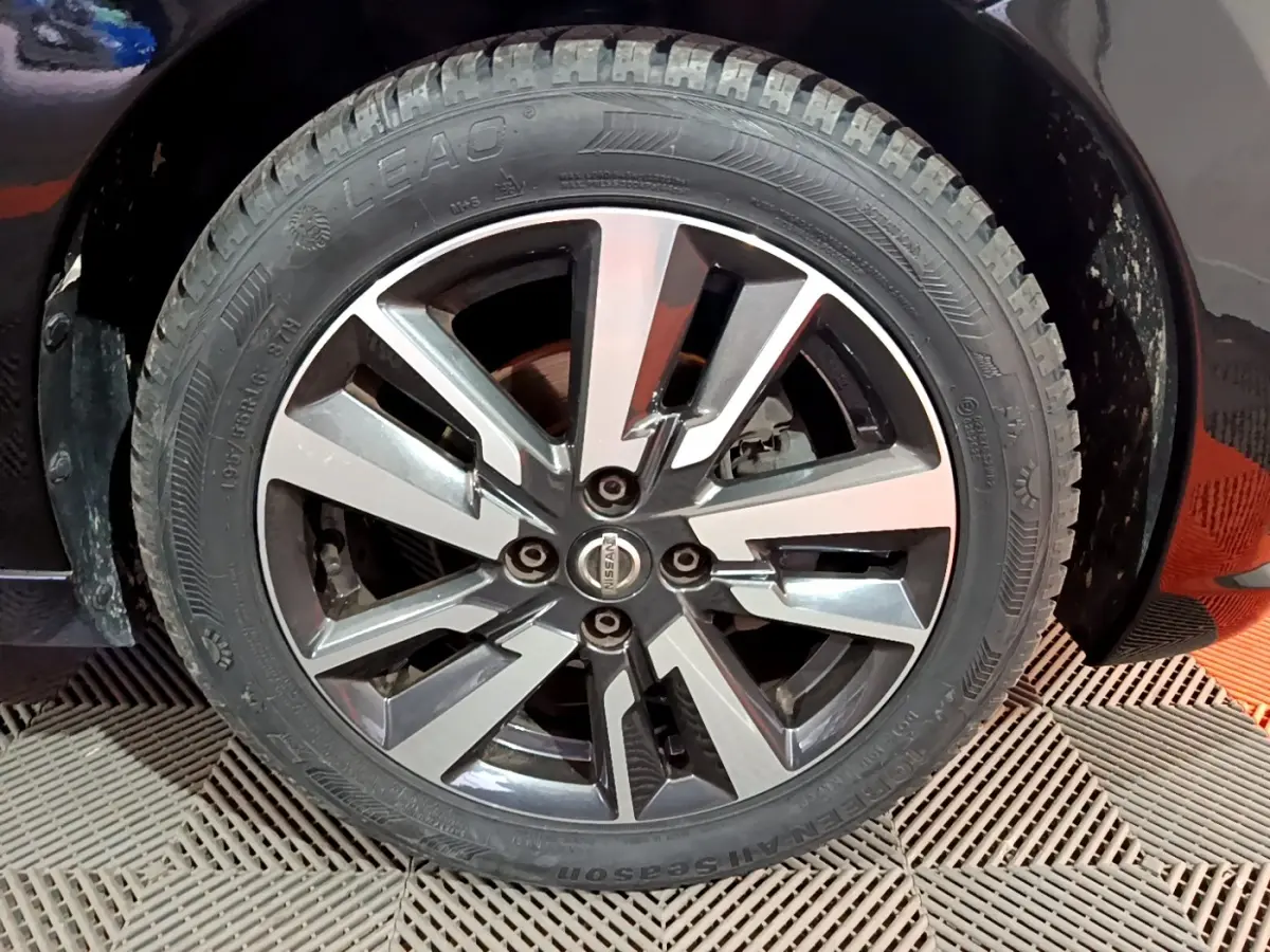 Gros plan sur la roue avant droite d’une Nissan Micra noire, avec jante alliage au design moderne bicolore.