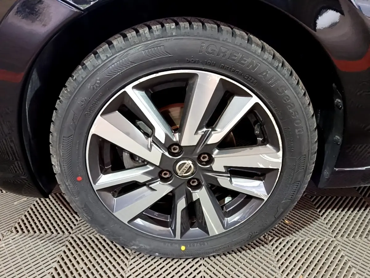 Gros plan sur la roue avant droite d'une Nissan Micra noire, mettant en valeur la jante alliage au design moderne.