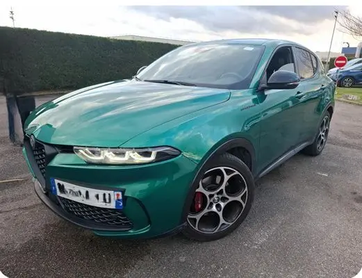 Vue 3/4 avant d'une Alfa Romeo Tonale 1.5 MHEV 130 TCT7 vert foncé avec jantes distinctives en intérieur showroom.