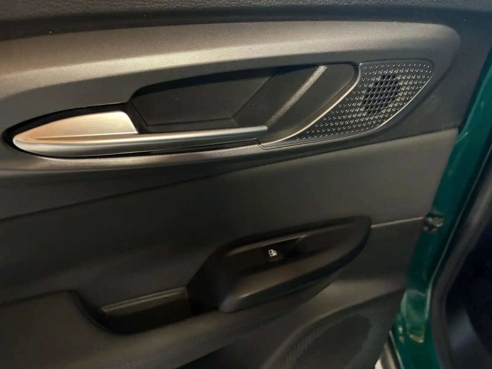Gros plan sur la poignée intérieure côté gauche de la porte avant d’une Alfa Romeo Tonale vert foncé, avec bouton de verrouillage.