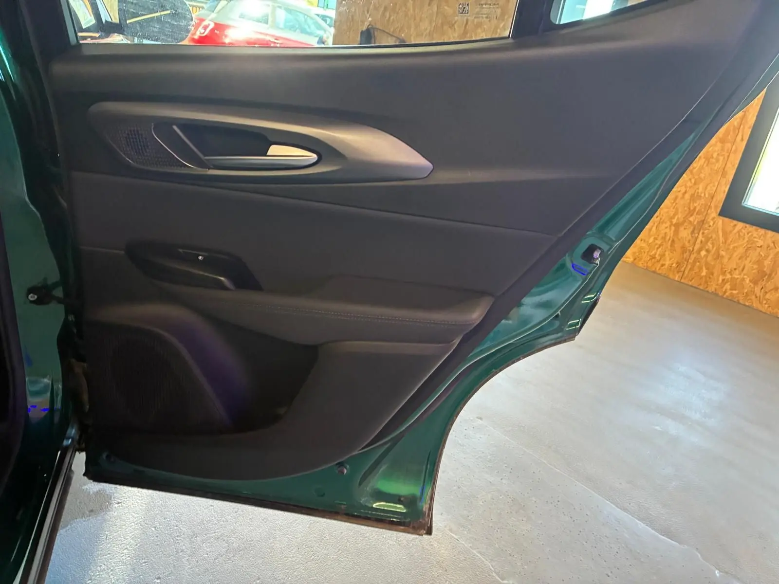 Vue intérieure de la porte arrière gauche d'une Alfa Romeo Tonale 2022 vert foncé avec garniture noire.