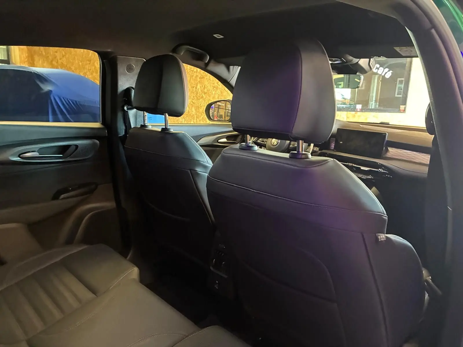 Vue intérieure arrière de l'Alfa Romeo Tonale 2022, sièges en cuir noir et tableau de bord visible côté droit.