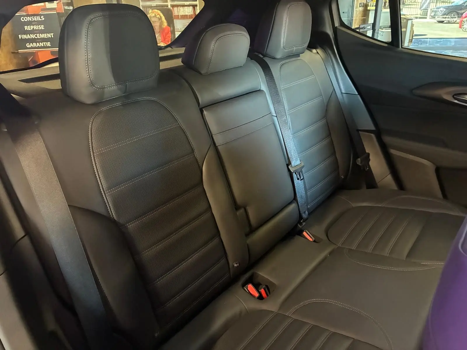 Vue intérieure arrière de l'Alfa Romeo Tonale 2022, sièges en cuir noir avec ceintures et appuie-têtes visibles.