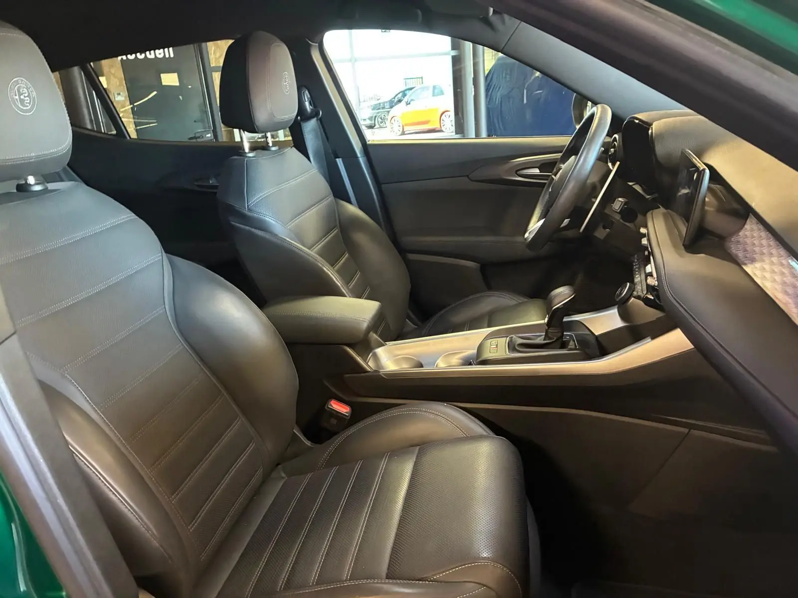 Vue intérieure côté conducteur de l'Alfa Romeo Tonale 2022, sièges cuir noir et console centrale avec levier de vitesse.