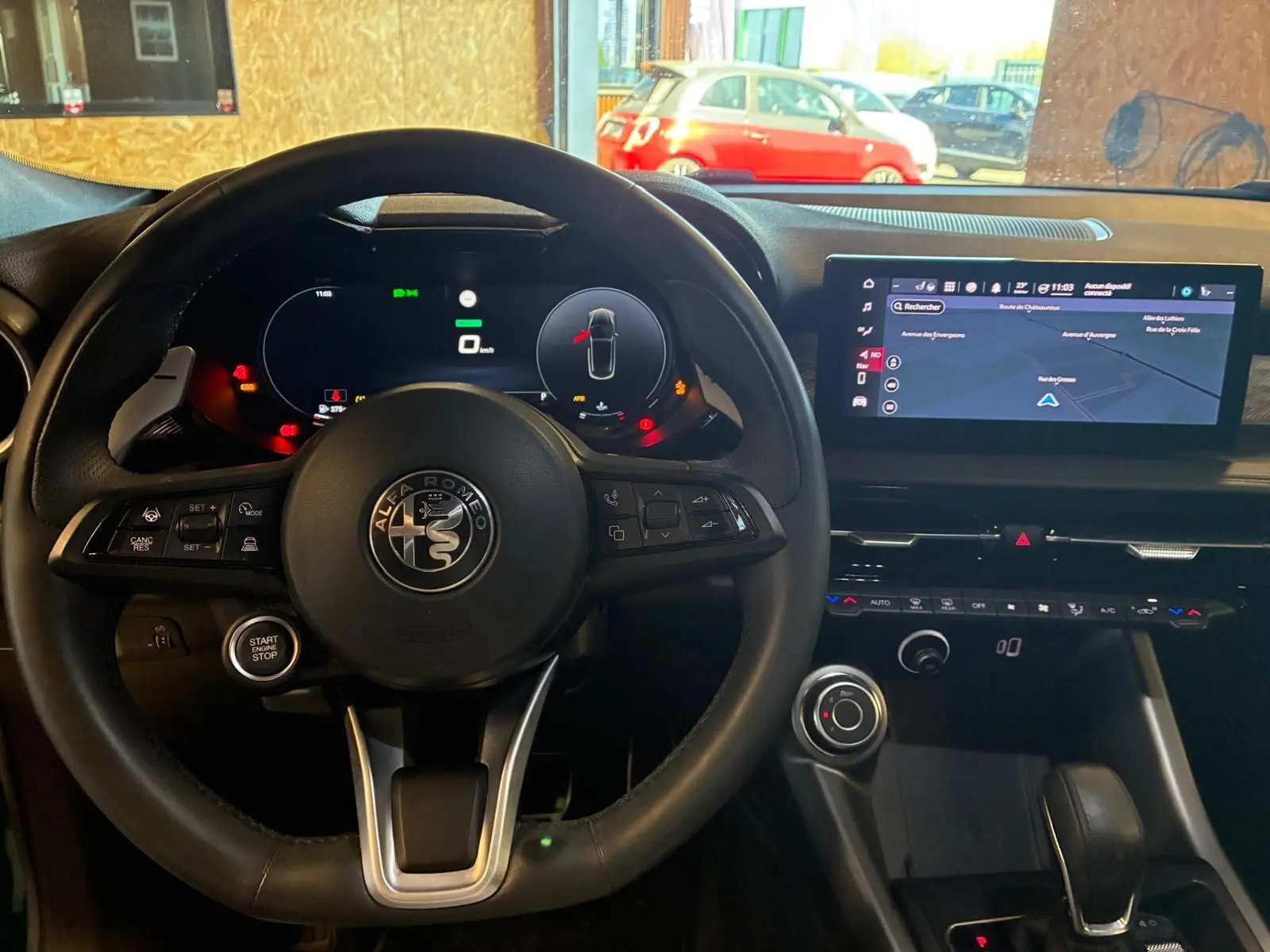 Vue intérieure centrée sur le volant noir d'Alfa Romeo Tonale 2022 avec tableau de bord digital et écran GPS lumineux.
