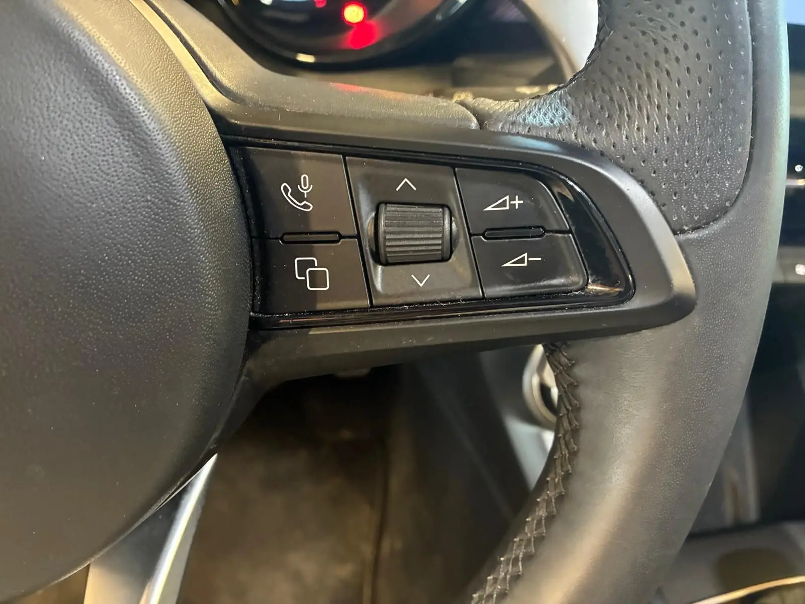 Gros plan sur les commandes gauche du volant en cuir noir perforé de l'Alfa Romeo Tonale 2022.