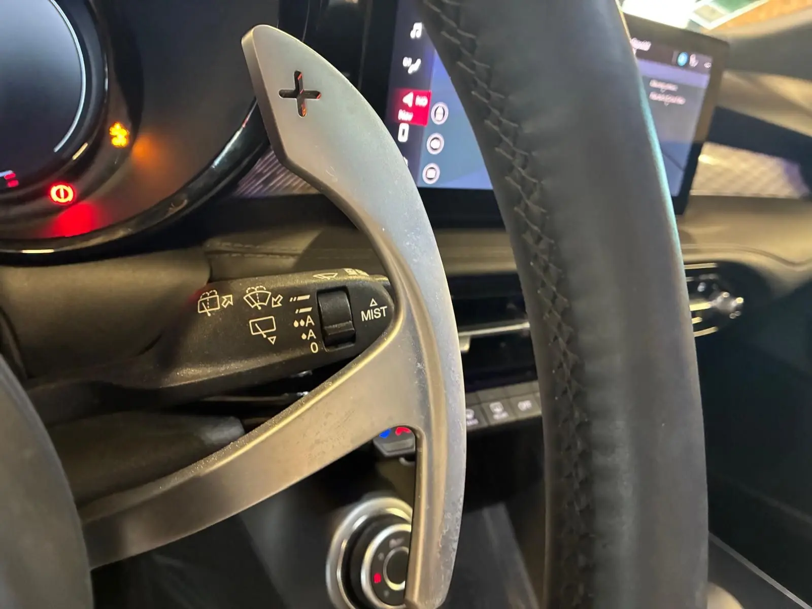 Gros plan sur la palette de changement de vitesses à droite du volant en cuir noir de l'Alfa Romeo Tonale vert foncé.