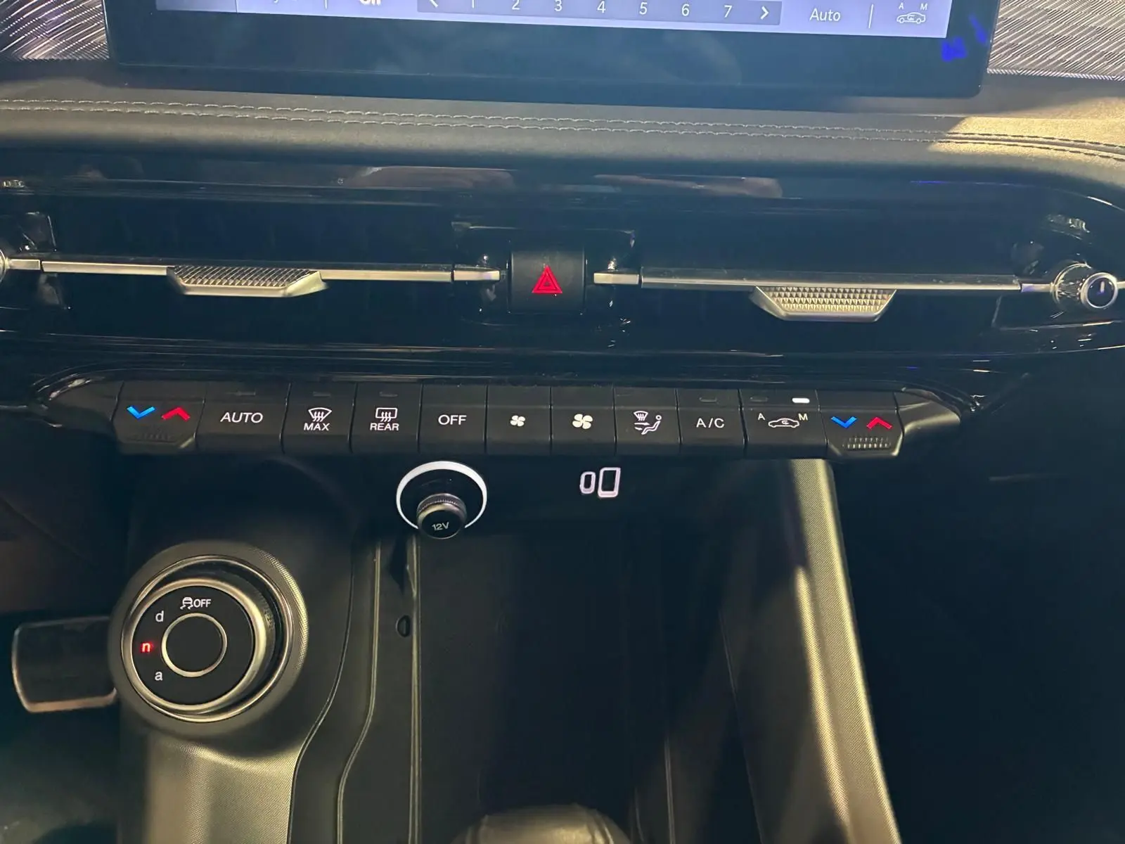 Vue rapprochée de la console centrale de l'Alfa Romeo Tonale 2022, avec commandes climatisation et bouton de sélection de mode de conduite.