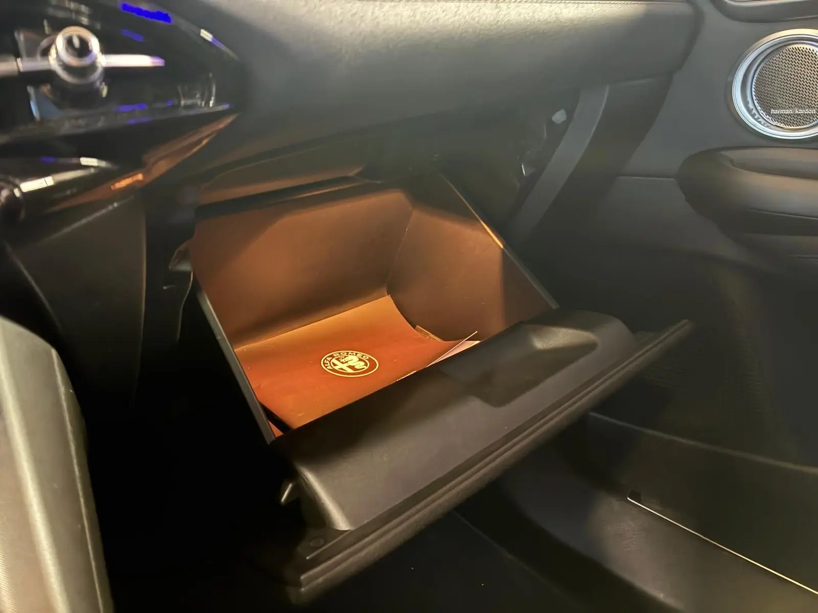Intérieur de l'Alfa Romeo Tonale 2022, vue sur la boîte à gants ouverte côté passager avec manuel de bord visible.