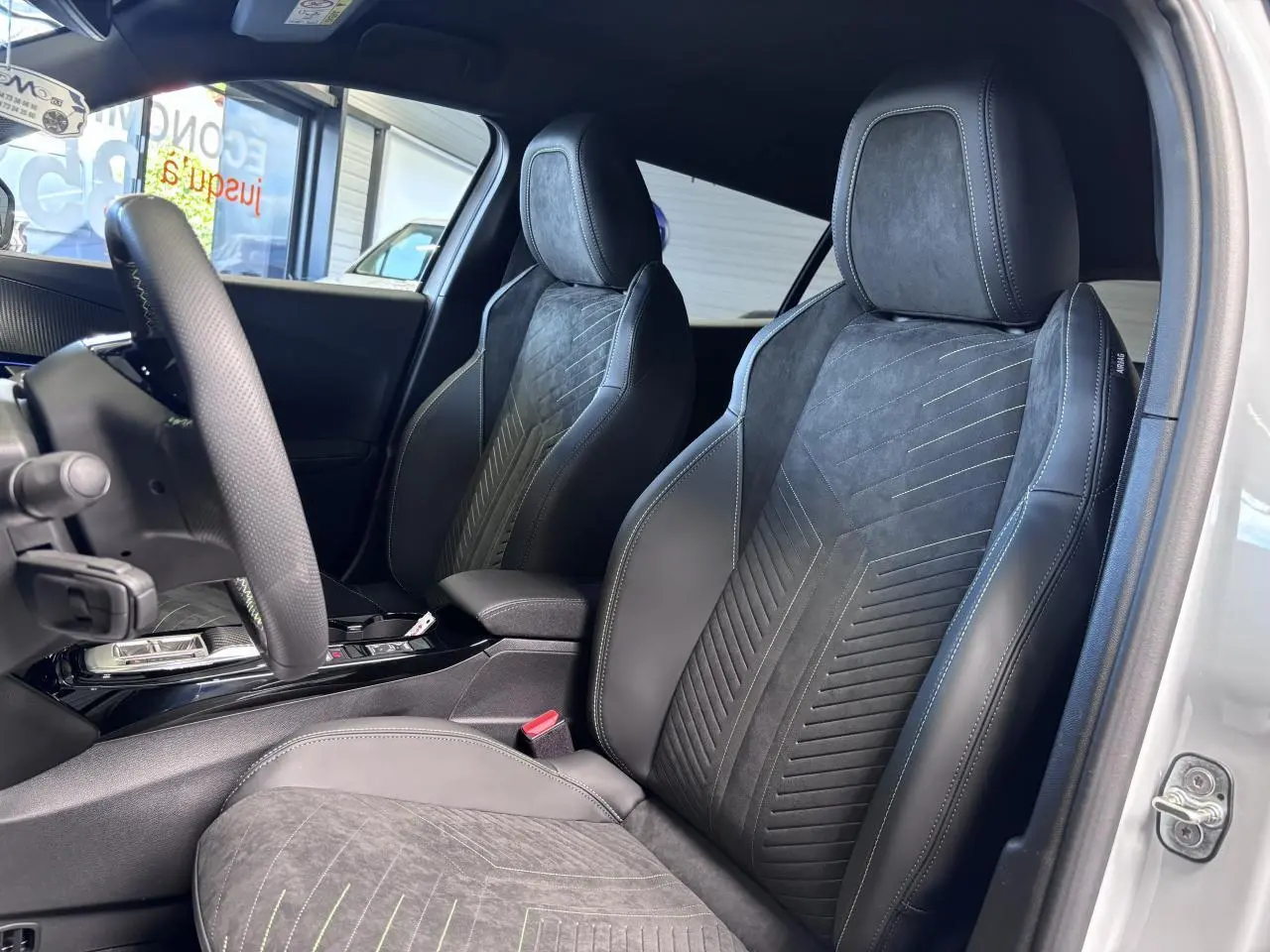 Vue intérieure côté gauche des sièges avant en Alcantara noir avec surpiqûres vertes dans un Peugeot 2008 hybride 2026.
