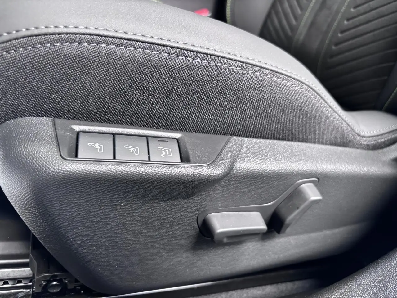 Détail des commandes de réglage électrique du siège conducteur en tissu noir du Peugeot 2008 Hybrid 2026.
