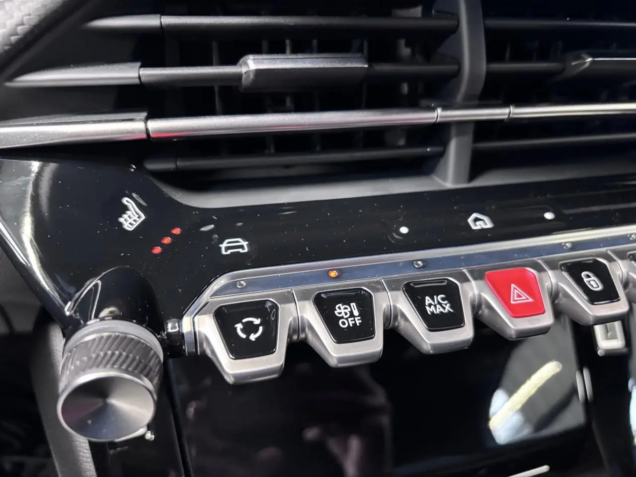 Gros plan sur la console centrale noire brillante du Peugeot 2008 1.2i Hybrid avec boutons de climatisation et siège chauffant.