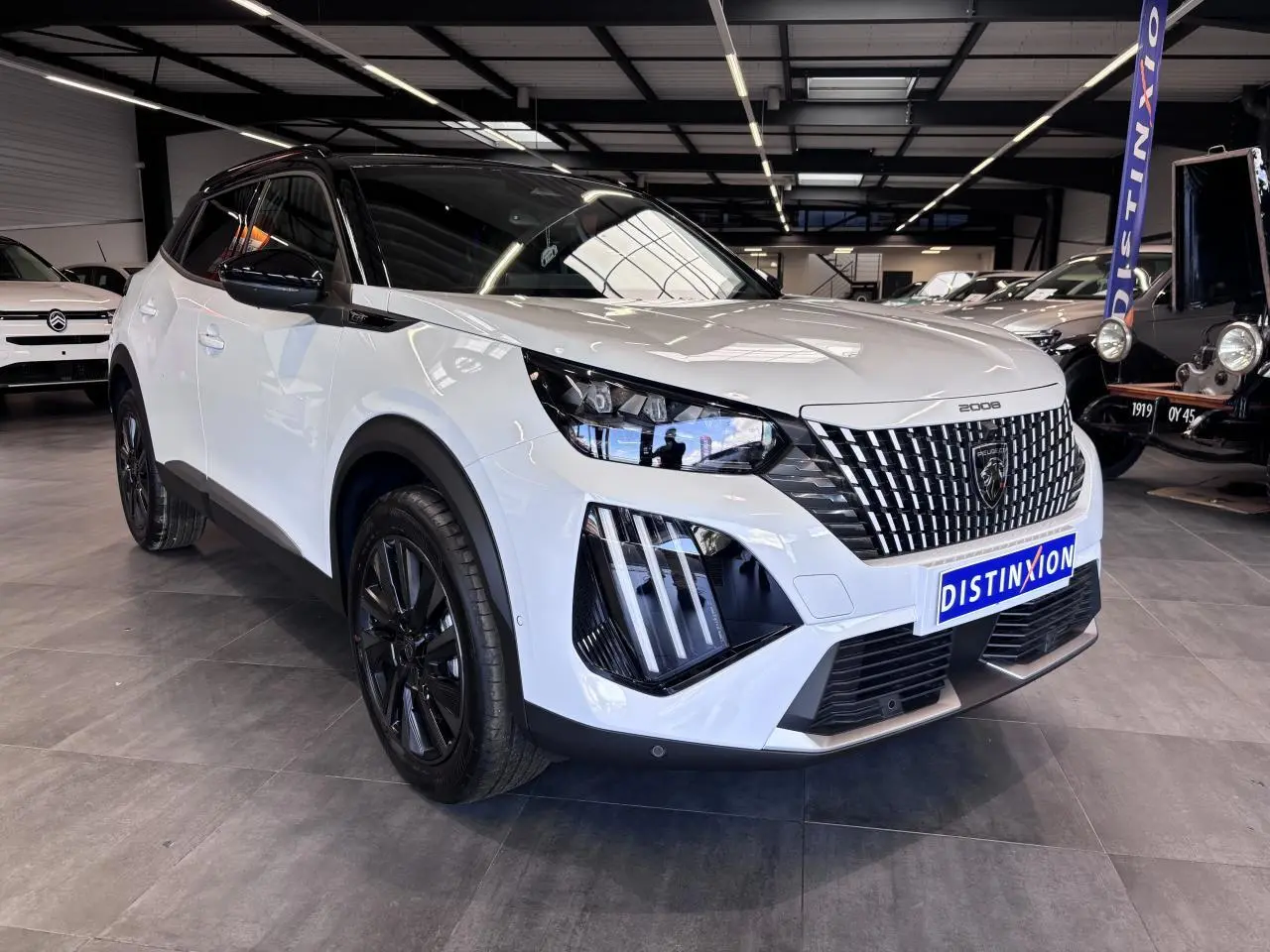 Peugeot 2008 hybride 2026 vue 3/4 avant gauche, carrosserie blanche et toit noir avec jantes noires.