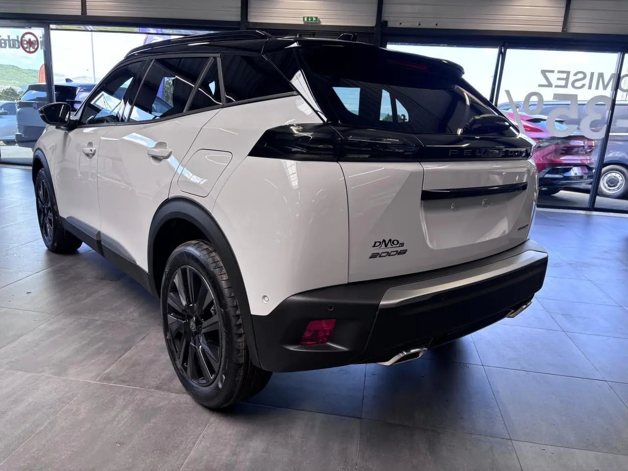 Vue 3/4 arrière droite du Peugeot 2008 hybride essence 2026 blanc avec toit noir et jantes alliage noires.