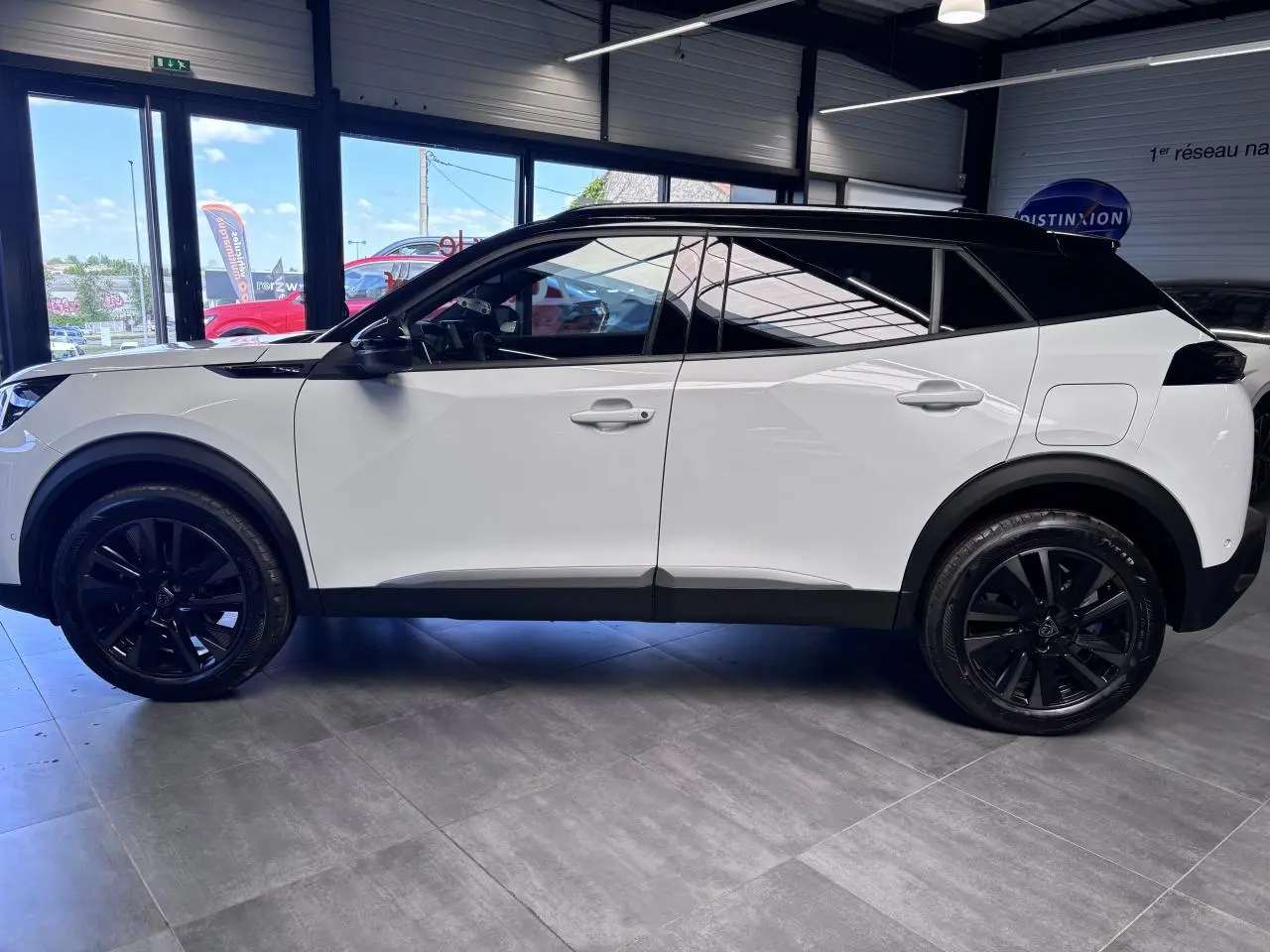 Peugeot 2008 hybride 2026 vue de profil côté gauche, carrosserie blanche avec toit et jantes noires.