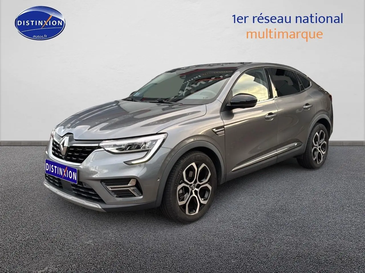 Renault Arkana gris en 3/4 avant droit, avec jantes alu distinctives et calandre noire brillante.