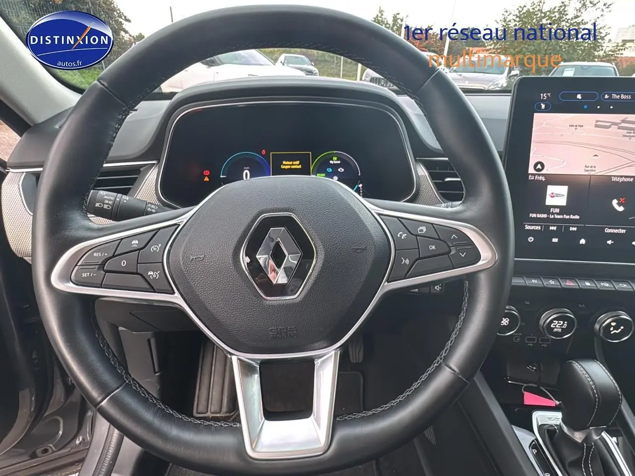 Vue intérieure centrée sur le volant cuir noir et l'écran tactile du Renault Arkana gris hybride 2022.