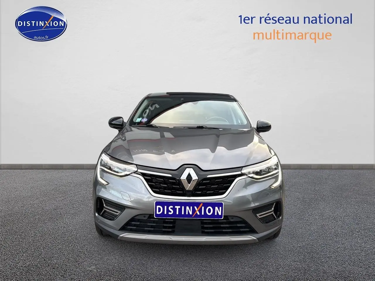 Vue avant d'un Renault Arkana gris 1.6 e-tech hybride 145 techno avec calandre noire et phares LED allumés.