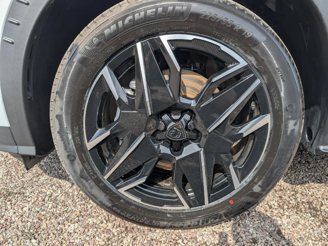 Gros plan sur la jante alliage noire et diamantée 19'' du Peugeot 5008 blanc hybride, avec pneu Michelin visible.