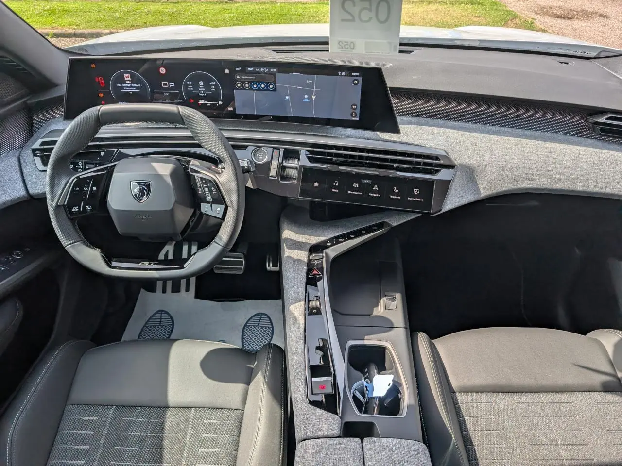 Vue intérieure avant du Peugeot 5008 blanc 2025, avec volant compact GT, écran panoramique incurvé et console centrale tissu Rimini.