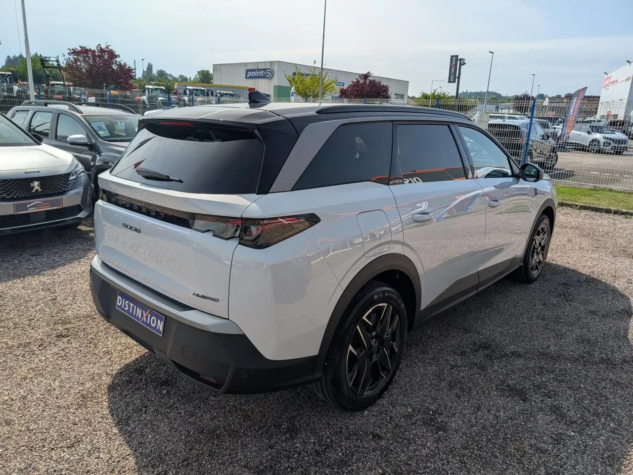 Vue 3/4 arrière droite du Peugeot 5008 blanc hybride 2025 avec toit noir et jantes alliage noires diamantées.