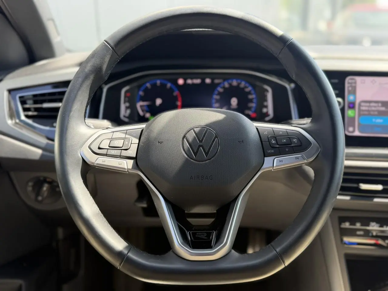 Vue rapprochée du volant cuir multifonctions noir du Volkswagen Taigo 2025 avec tableau de bord digital en arrière-plan.