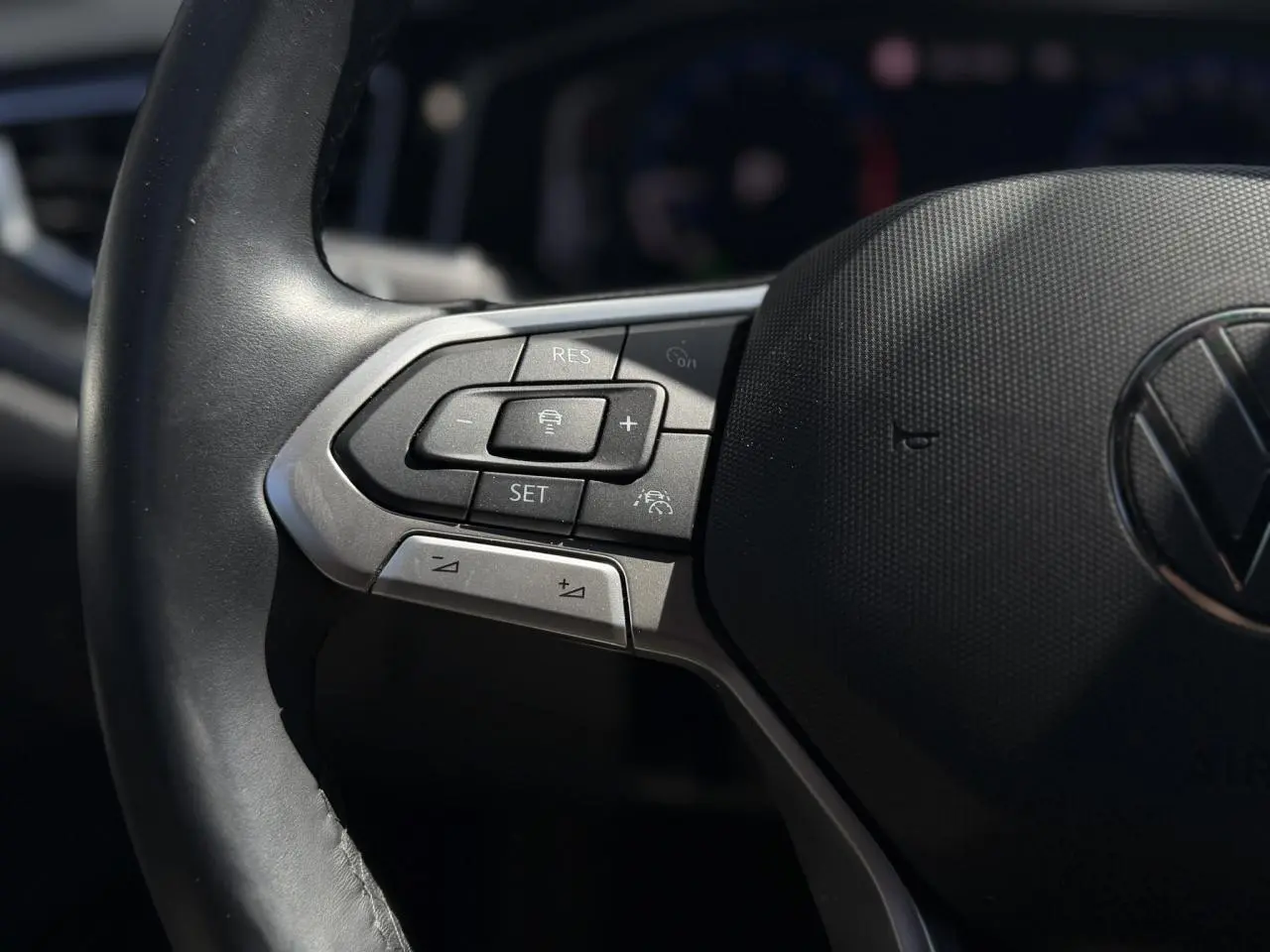 Gros plan sur les commandes du régulateur adaptatif au volant cuir du Volkswagen Taigo TSI 116 DSG R-Line 2025.