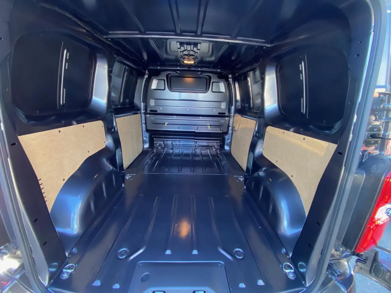 Vue intérieure arrière du fourgon Peugeot Expert gris titane, montrant l'espace de chargement vide avec parois partiellement protégées.