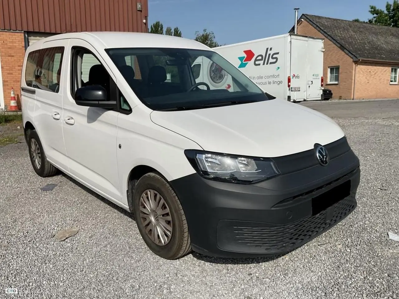 Volkswagen Caddy blanc Candy vue 3/4 avant droit avec pare-chocs noir mat et jantes acier.