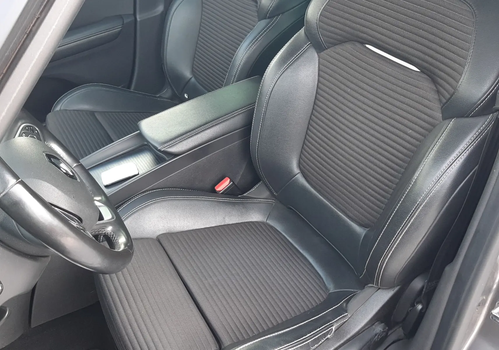 Vue intérieure côté conducteur du Renault Scenic IV 2020, sièges en cuir noir avec surpiqûres blanches et volant multifonction.