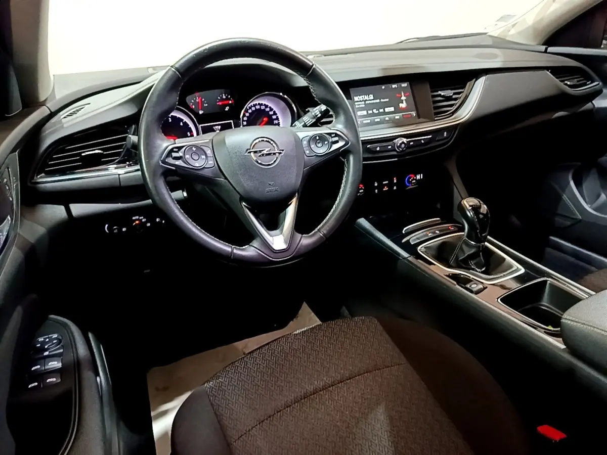 Vue intérieure avant de l’Opel Insignia 2019, tableau de bord noir avec volant cuir et levier de vitesse manuel.