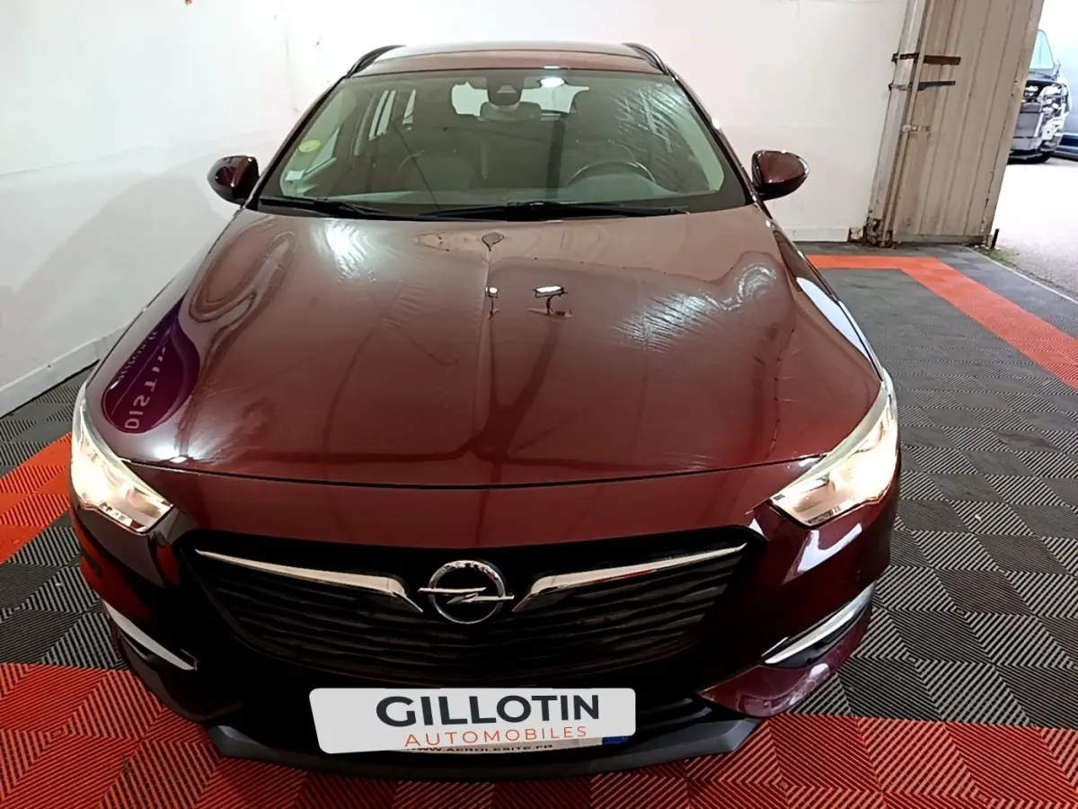 Vue avant d'une Opel Insignia rouge 2019 avec calandre noire et phares allumés dans un garage.
