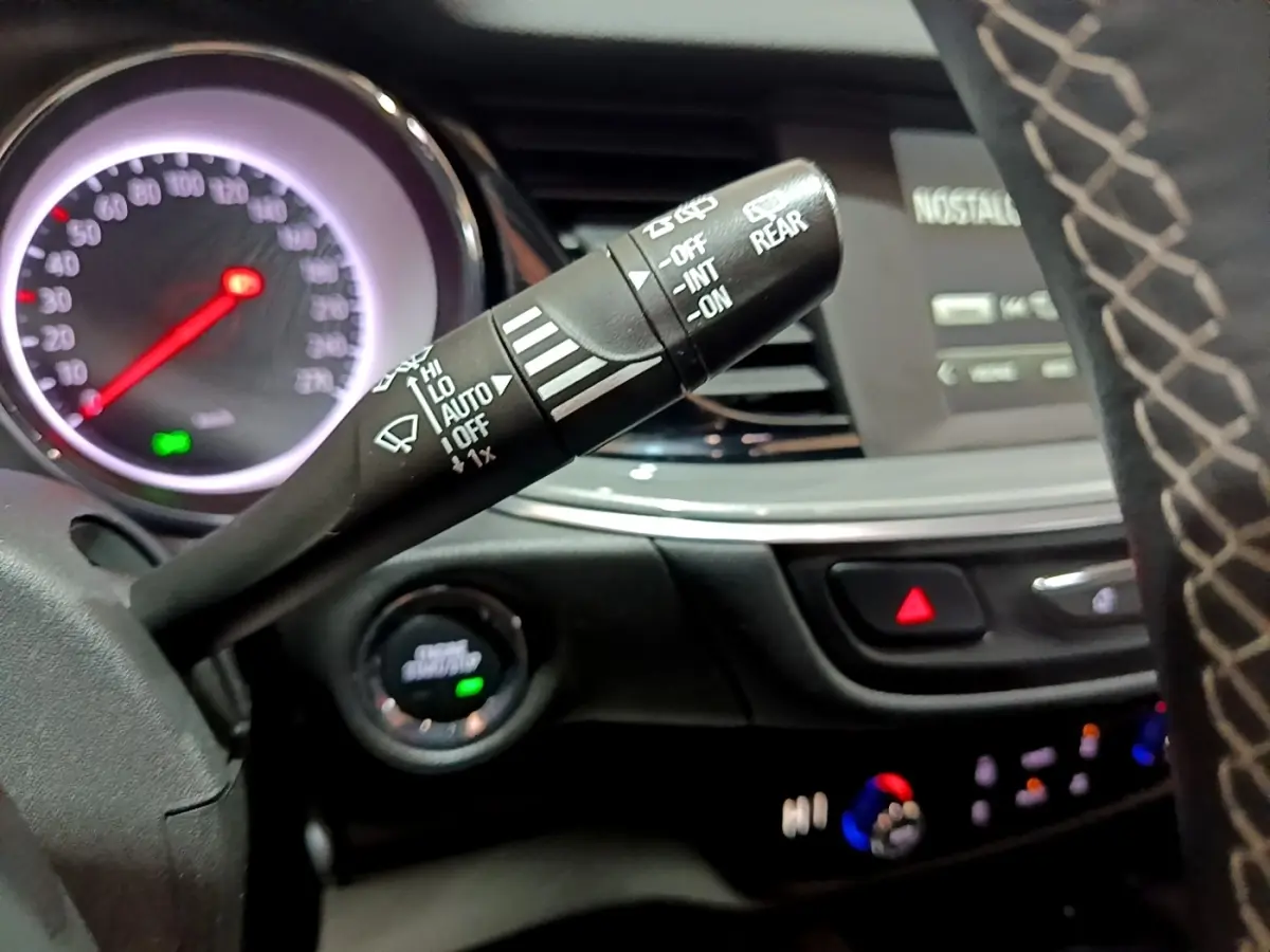 Gros plan sur la commande d’essuie-glace à gauche du volant dans l’habitacle sombre d’une Opel Insignia rouge 2019.