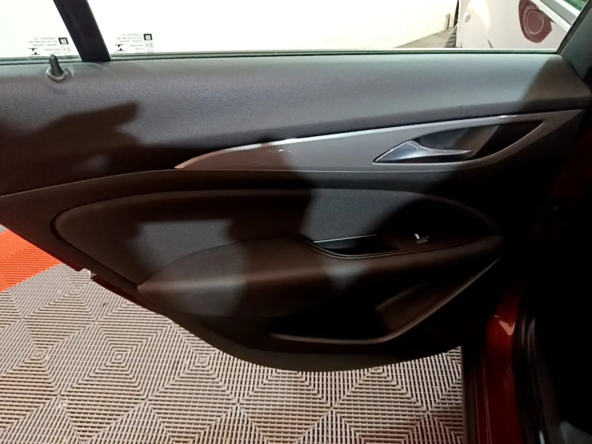 Vue rapprochée de la porte arrière droite noire de l’Opel Insignia rouge, mettant en valeur la poignée et les commandes de vitre.