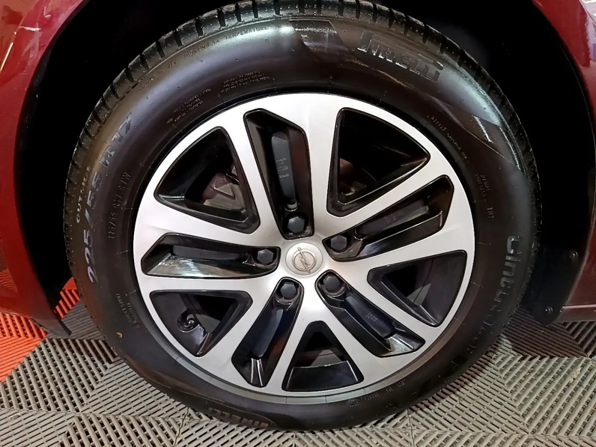Gros plan sur la roue avant droite d’une Opel Insignia rouge, mettant en valeur le pneu et l’aile du véhicule.