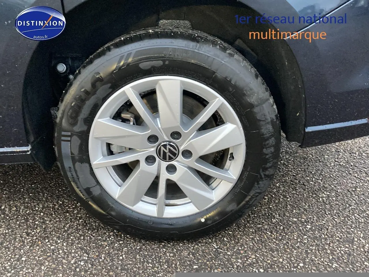 Gros plan sur la roue avant gauche d’un Volkswagen Caddy bleu métallisé avec jante alliage argentée.