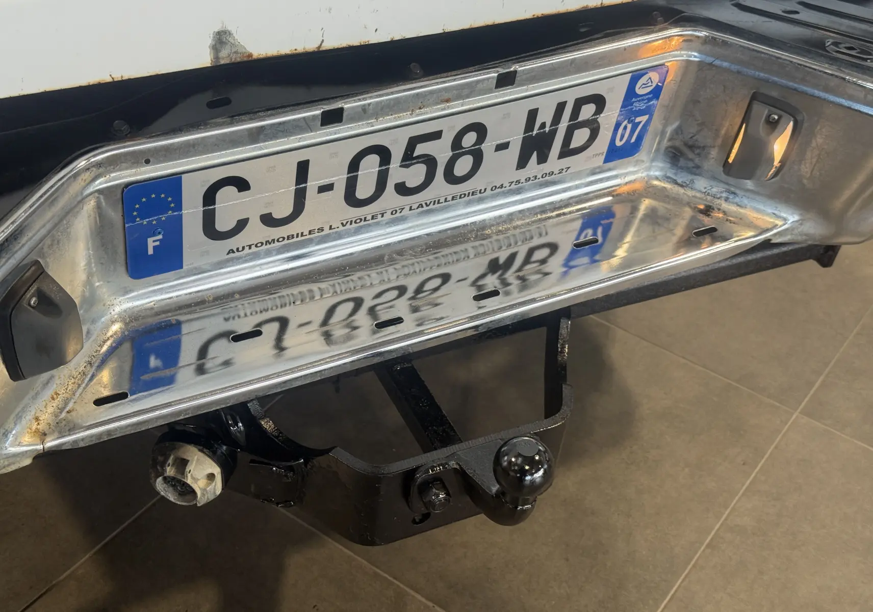 Gros plan sur la partie arrière blanche du Nissan Navara NP300 2002 avec attelage de remorque et plaque d'immatriculation française.