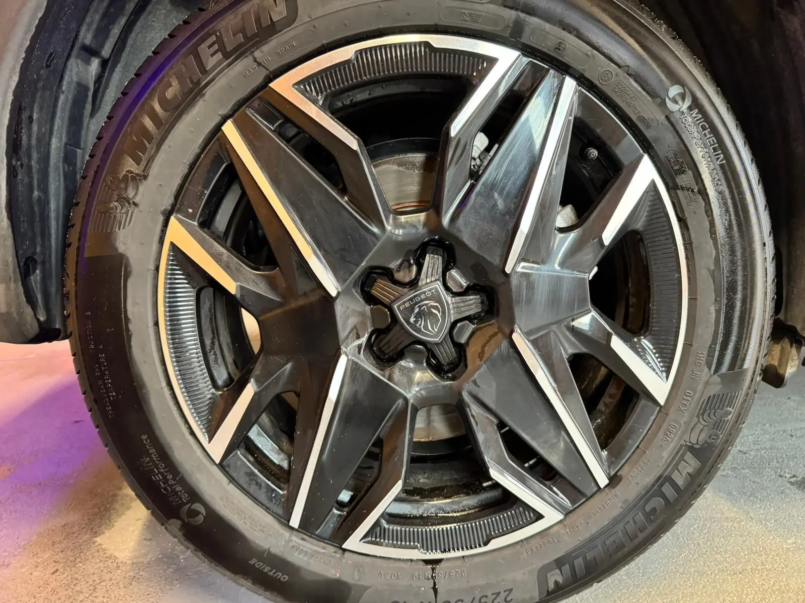 Gros plan sur la jante noire et argentée du Peugeot 5008 1.2 HYBRID 136 GT gris avec logo central lion.