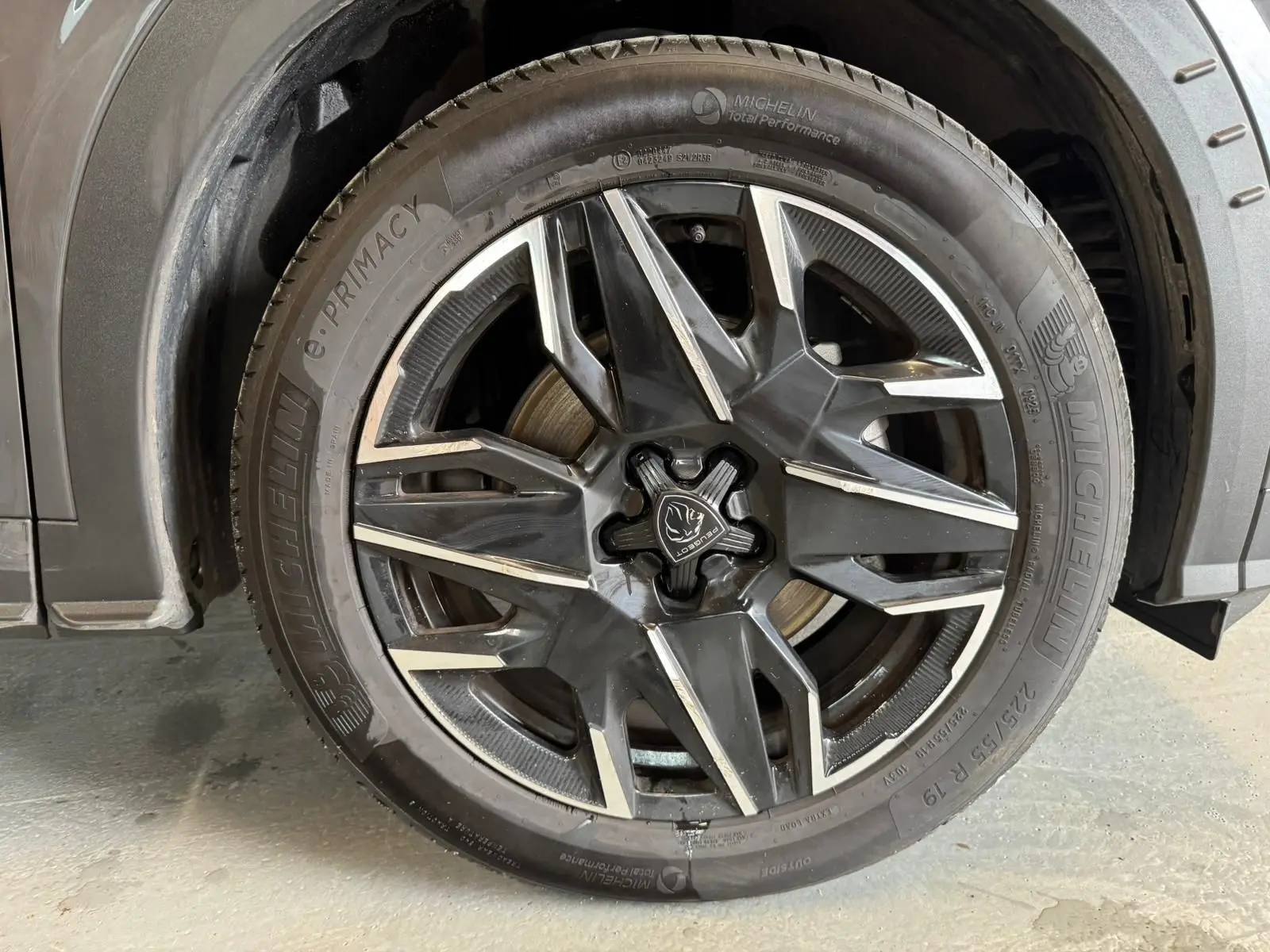 Gros plan sur la roue avant gauche gris foncé du Peugeot 5008 1.2 Hybrid 136 GT avec jante alliage noire et détails argentés.