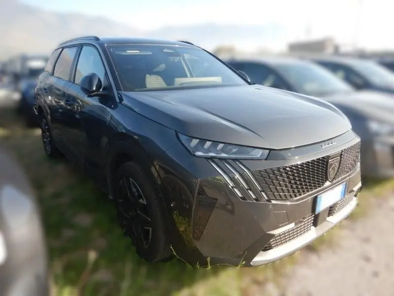 Peugeot 5008 1.2 Hybrid 136 GT gris vue 3/4 avant droit, avec calandre distinctive et phares LED marqués.