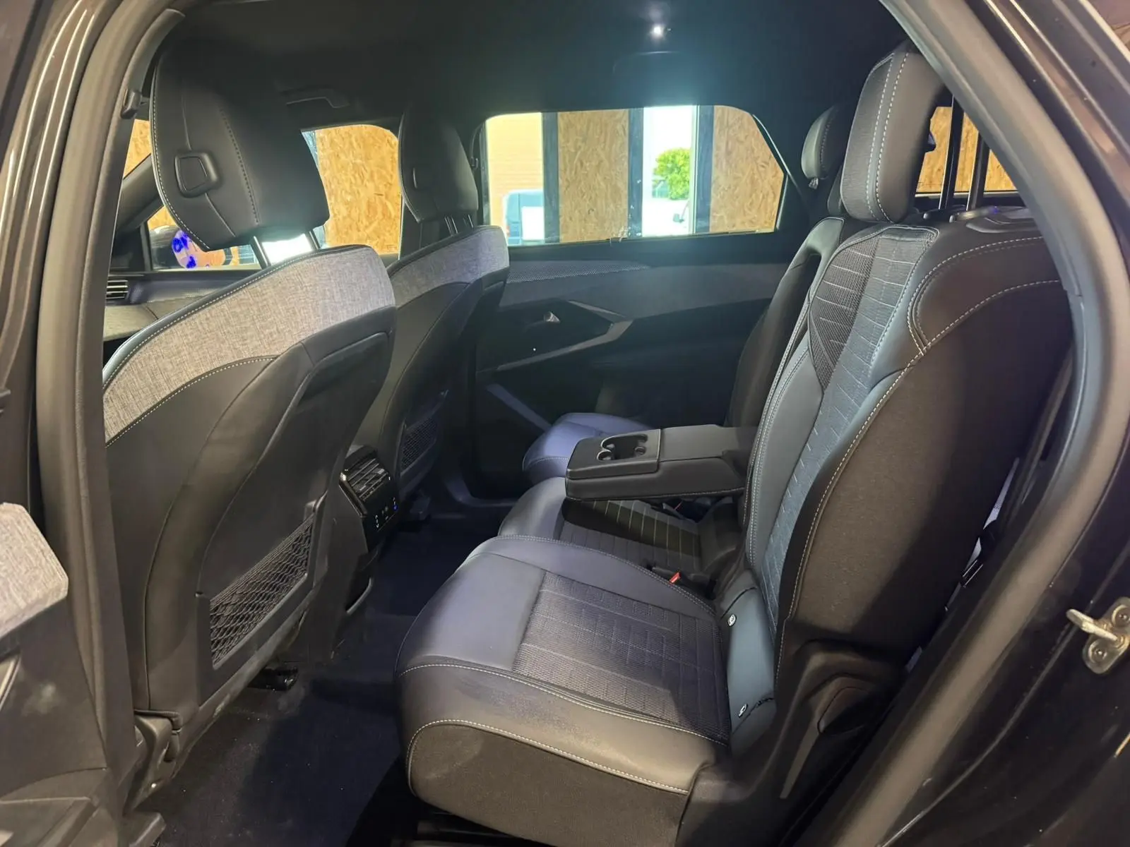 Vue intérieure côté droit des sièges arrière en tissu noir avec accoudoir central du Peugeot 5008 1.2 Hybrid 136 GT 2025.