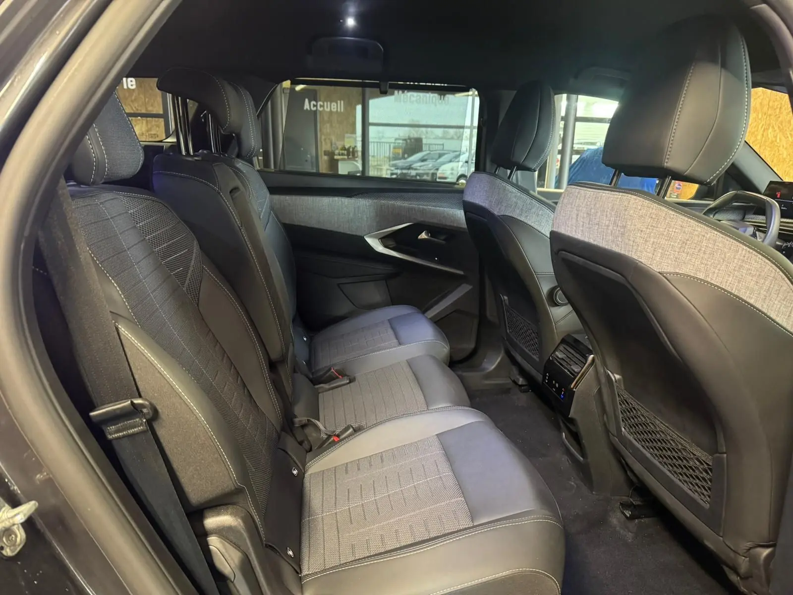 Vue intérieure arrière côté gauche du Peugeot 5008 gris 2025, montrant les sièges tissu noir et les finitions modernes des portes.