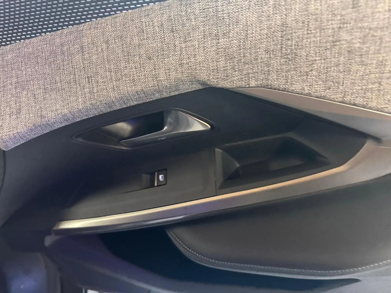 Détail de la porte intérieure côté gauche du Peugeot 5008 gris, avec poignée argentée et commande de vitre.