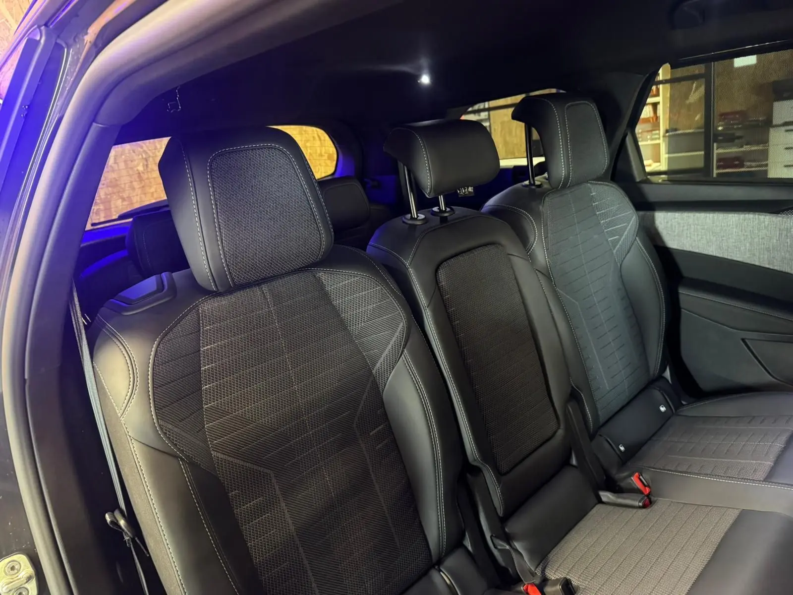 Vue intérieure des sièges arrière en tissu noir avec surpiqûres blanches du Peugeot 5008 1.2 Hybrid 136 GT gris 2025.